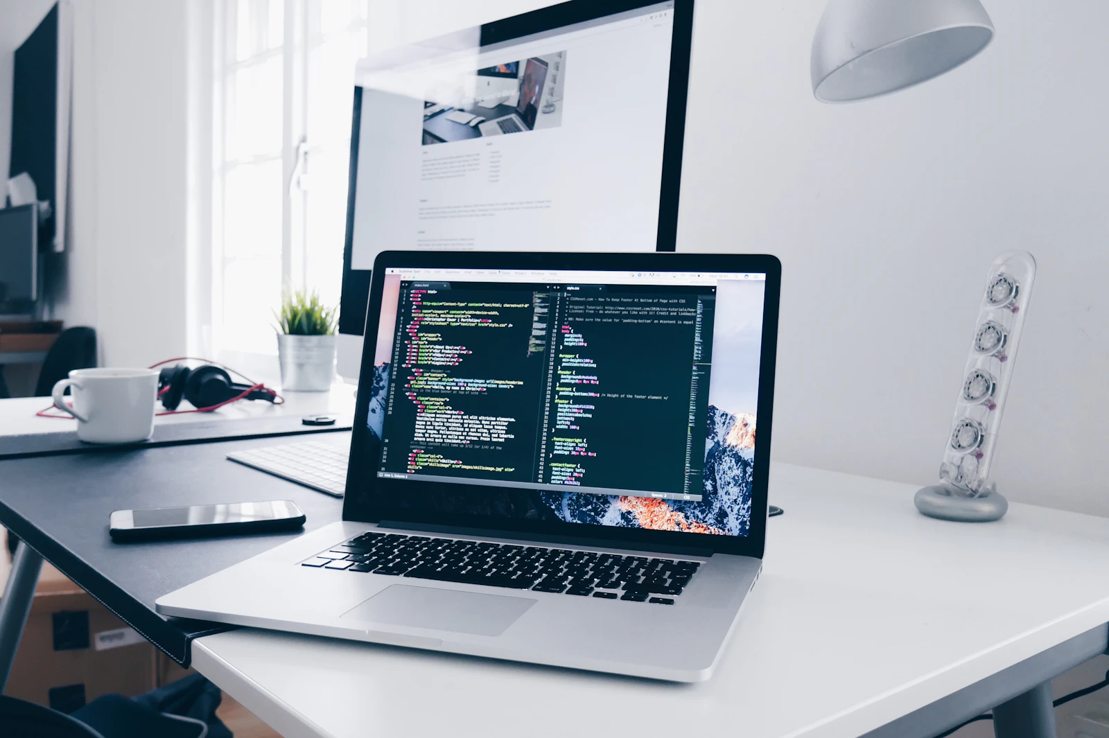 Um MacBook com linhas de código no ecrã numa secretária